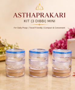 Three transparent mini dibbi jars with blue lids in a row, part of an Asthaprakari kit for daily pooja. Background includes a Buddha statue, white petals, and a labeled Punjani Jain Store box.