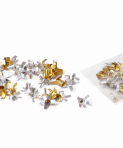 Silver and gold metallic confetti scattered on a white surface, with a clear plastic bag nearby (party decorations).