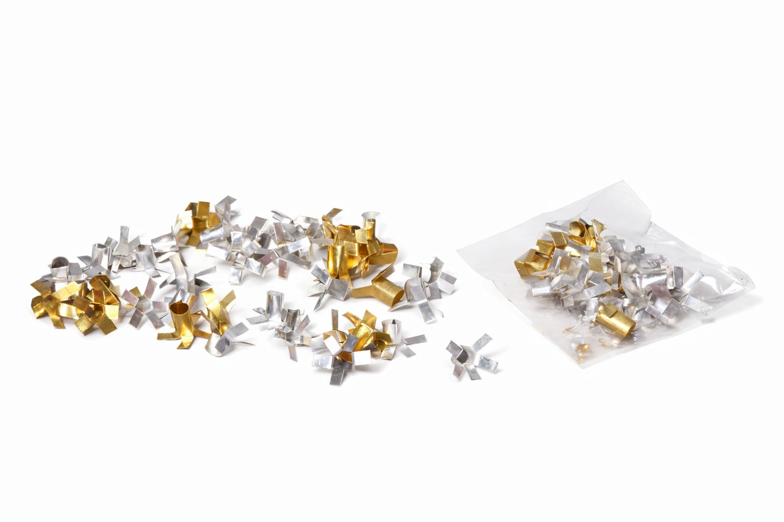 Silver and gold metallic confetti scattered on a white surface, with a clear plastic bag nearby (party decorations).
