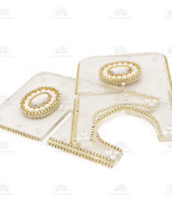 Close-up of clear acrylic decorative letters with gold rhinestone borders and white gem accents on a white background