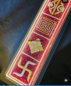 Close-up of a red and gold decorative band with Greek key pattern and floral motif on a dark background.