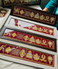 Decorative framed textile panels with gold embroidery on red fabric, showing symbols and floral motifs arranged in a strip-like layout.