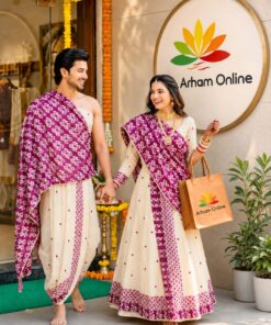 Couple in cream and magenta traditional outfits walk hand in hand outside an Arham Online storefront adorned with marigold garlands.