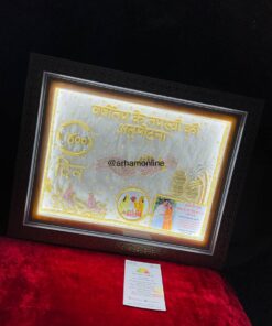 Ornate framed gold-embroidered plaque with Hindi script, watermark @arhamonline, resting on red velvet surface.
