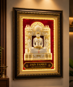 Ornate framed Jain statue on a red velvet background with gold detailing and a plaque reading 'JAIN FAMILY' beneath.
