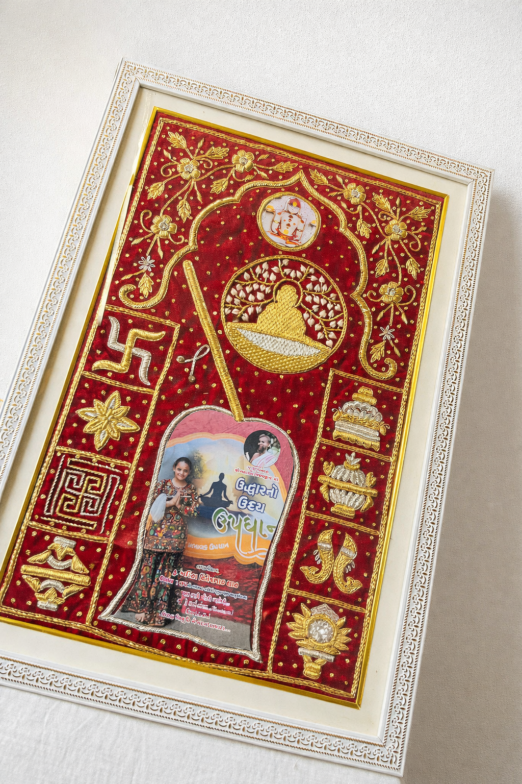 Framed decorative red velvet textile with gold embroidery and floral motifs, displayed in an ornate white frame.