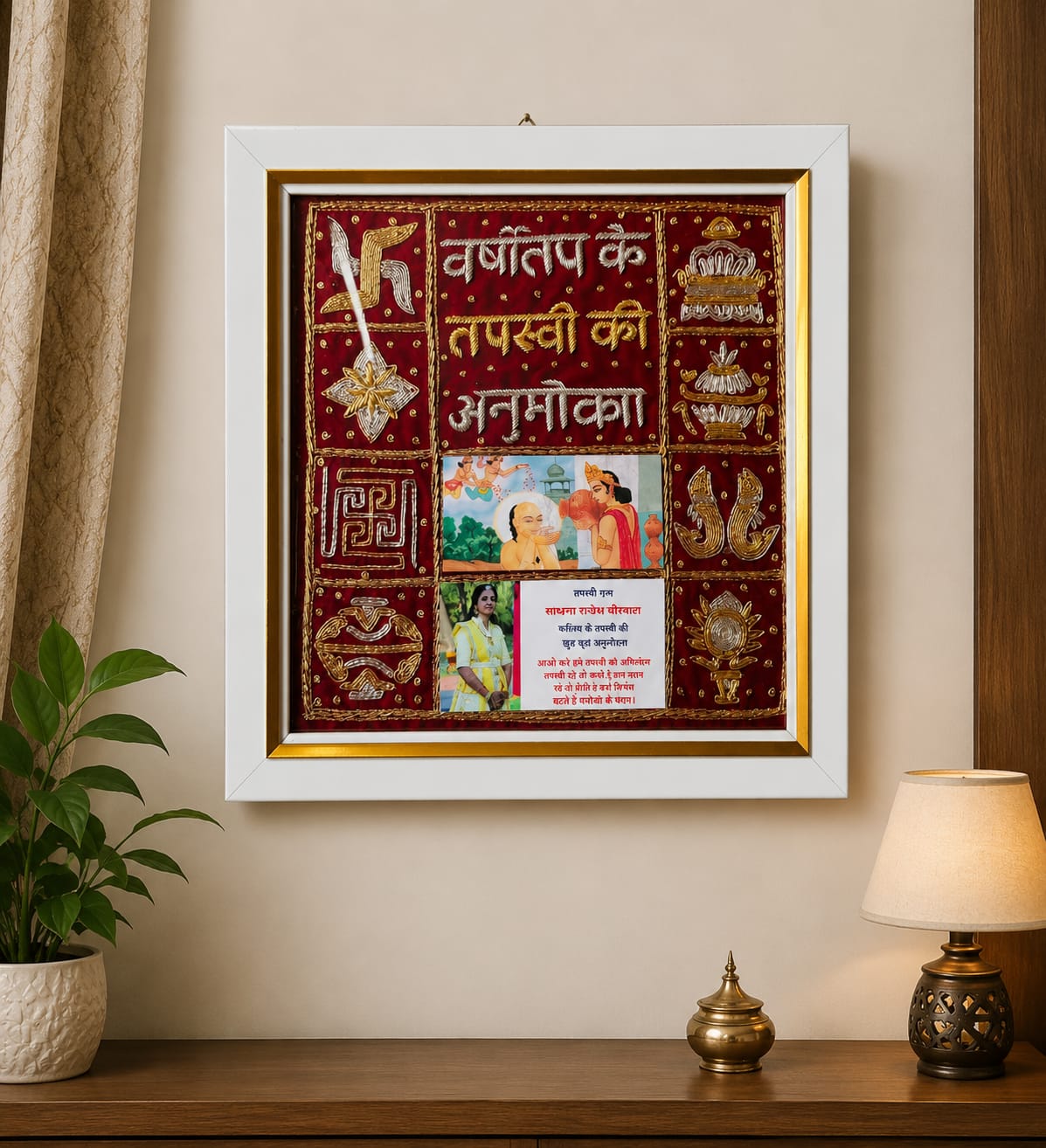 Decorative framed textile wall art with maroon and gold embroidery, Hindi text, and traditional motifs, mounted on a beige wall.