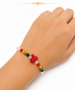 Rainbow beaded bracelet with a red knot charm on a wrist.