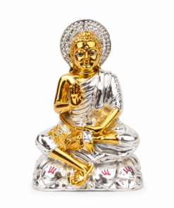 Gold and silver Buddha statue seated cross-legged with right hand raised in blessing (abhaya mudra) and glowing halo against a white background.