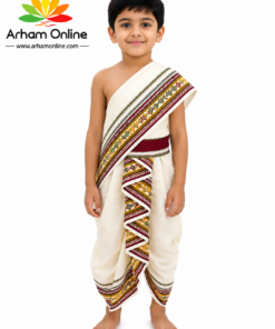 Young boy in cream traditional Indian outfit with a colorful patterned sash, standing barefoot against a white background; Arham Online logo on the left.