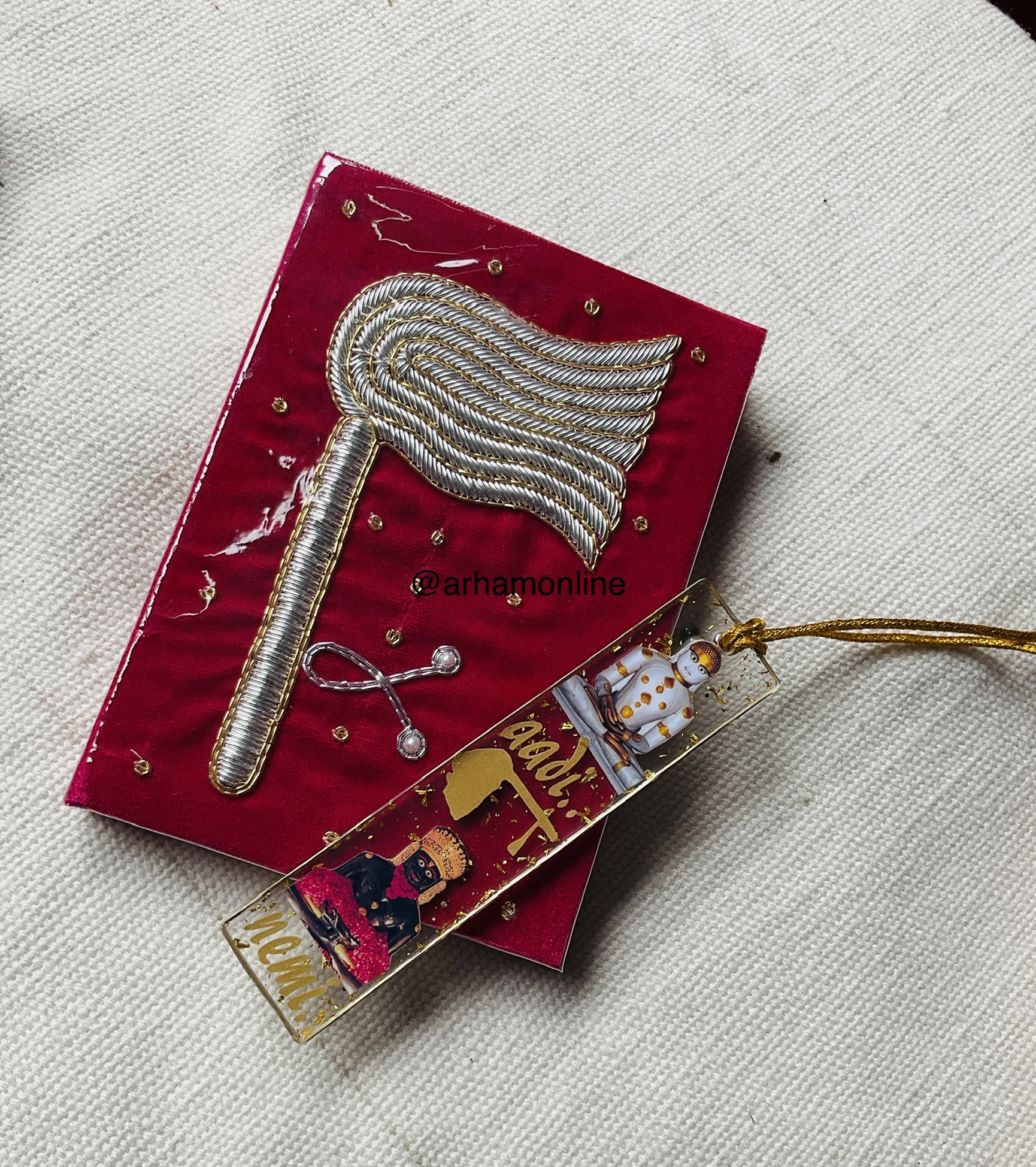 Red velvet card featuring a braided silver feather brooch with gold edging, set on light fabric background.