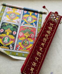 Partially unrolled colorful religious scroll with temple medallions and floral borders, placed beside a red velvet pouch with gold embroidery on fabric.