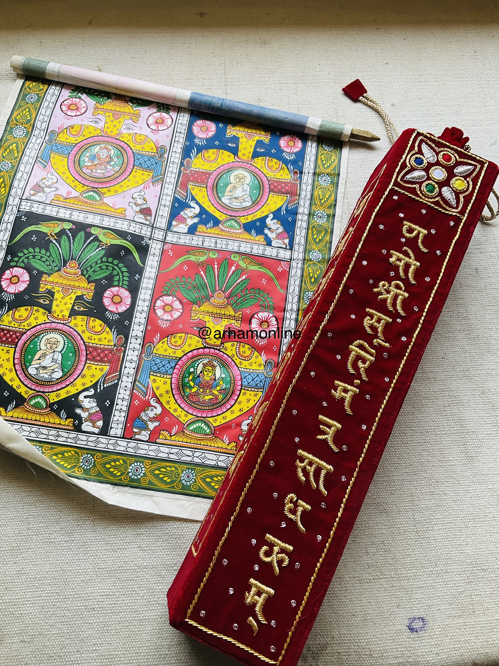 handwork book mark Colorful traditional Indian artwork with framed deity illustrations, alongside a red velvet embroidered pouch with gold script