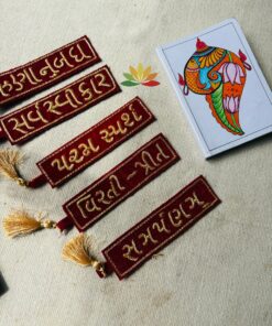 Red velvet decorative banners with gold embroidery and tassels on a beige fabric, next to a colorful elephant illustration on a card.