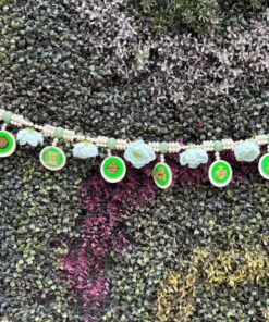 Decorative bead garland with round green-medallion charms draped across a colorful succulent wall.